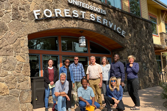 A group of people pose in front of a stone building that says United States Forest Service