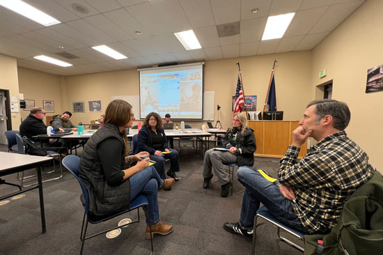 Four people talk sitting in chairs in a circle inside a meeting space