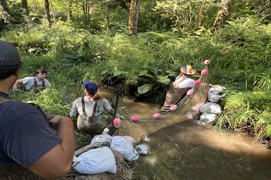a crew works in a stream with nets and sandbags to conduct fish monitoring